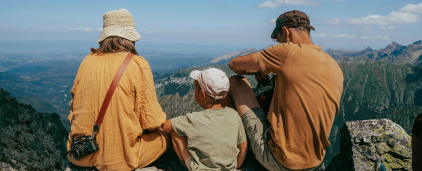 Three people sitting looking at mountains.