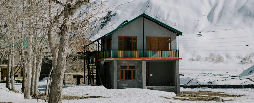 A small green cottage in a wintery scenery.