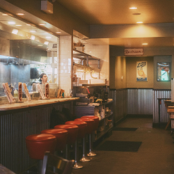 A dimly lit diner with red stools